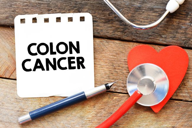 note card saying Colon Cancer laying on a wood desk with a stethoscope