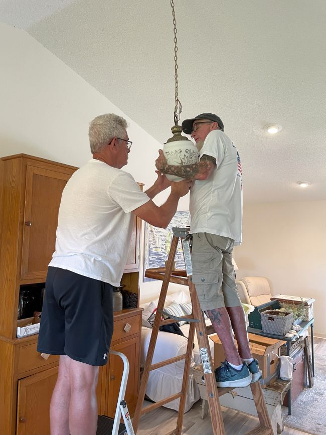 two men hanging an antique ceiling light