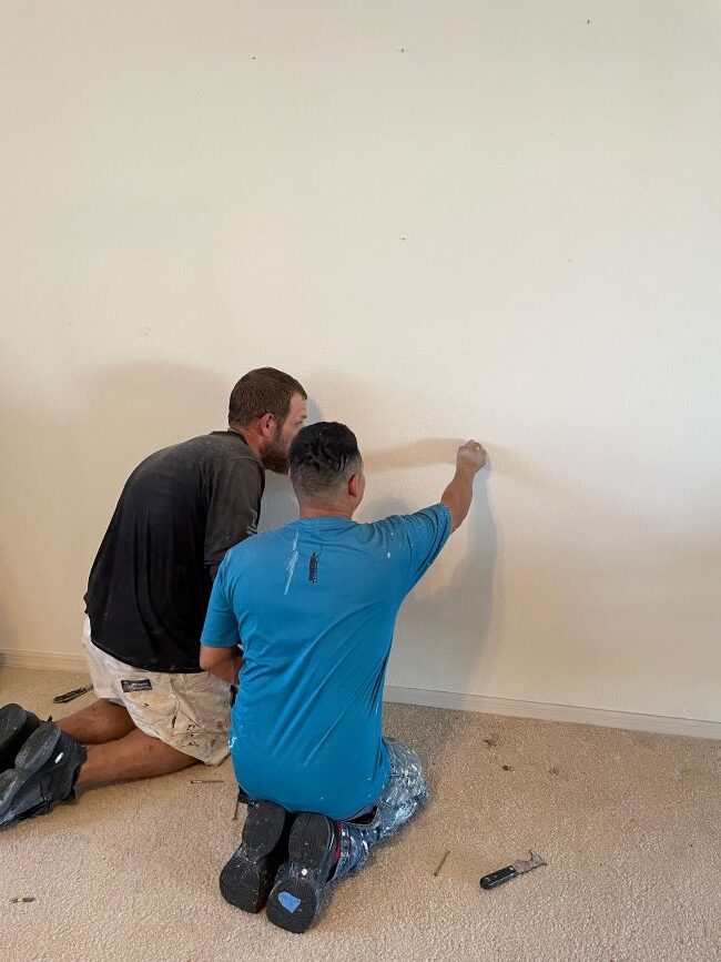 two guys looking for studs in the wall