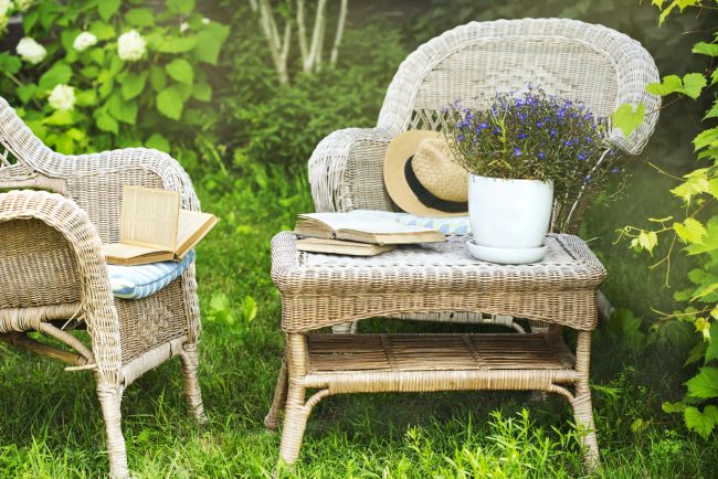 old wicker chairs and coffee table accented with old books and a pot of blue flowers