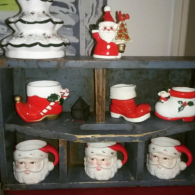 old wooden carrier turned on its side to make a display. Display holds vintage Christmas mugs and ceramic boots