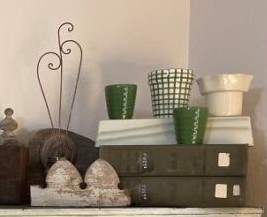 Vintage green books stacked with ceramic cups and decor pieces, adding character to a cream and green spring display