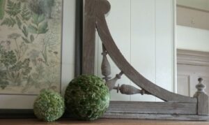Vintage botanical artwork displayed with two textured green decorative spheres for a soft cream and green spring vignette