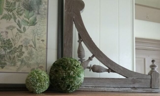 Vintage botanical artwork displayed with two textured green decorative spheres for a soft cream and green spring vignette