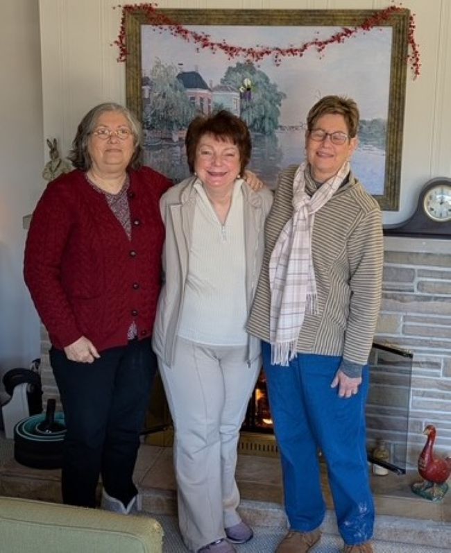 three old friends standing in front of a fireplace