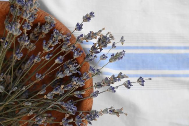 old wooden bowl filled with lavender sprigs, placed on blue and white linen runner