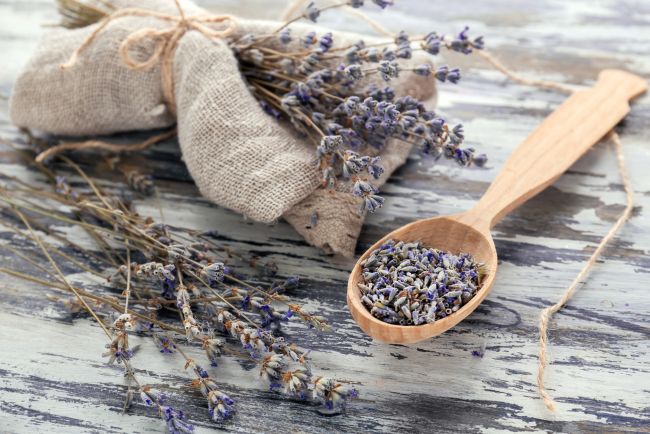 wooden spoon filled with lavender buds, muslin wrapped dried lavender sprigs