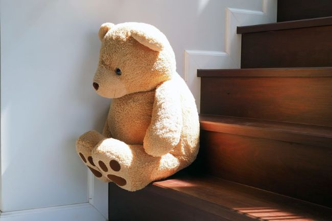 large teddy bear perched on a wooden staircase