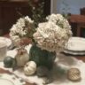 close up of vintage pottery pitcher filled with faux hydrangea and artificial greenery