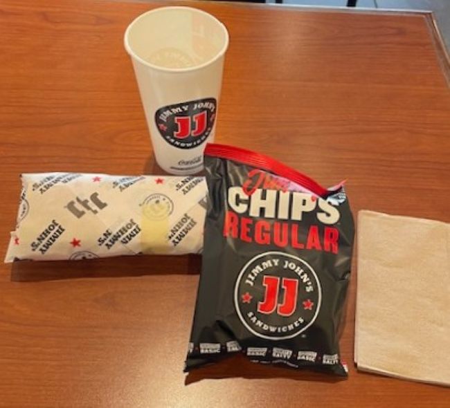 wrapped sandwich, chips and a drink cup