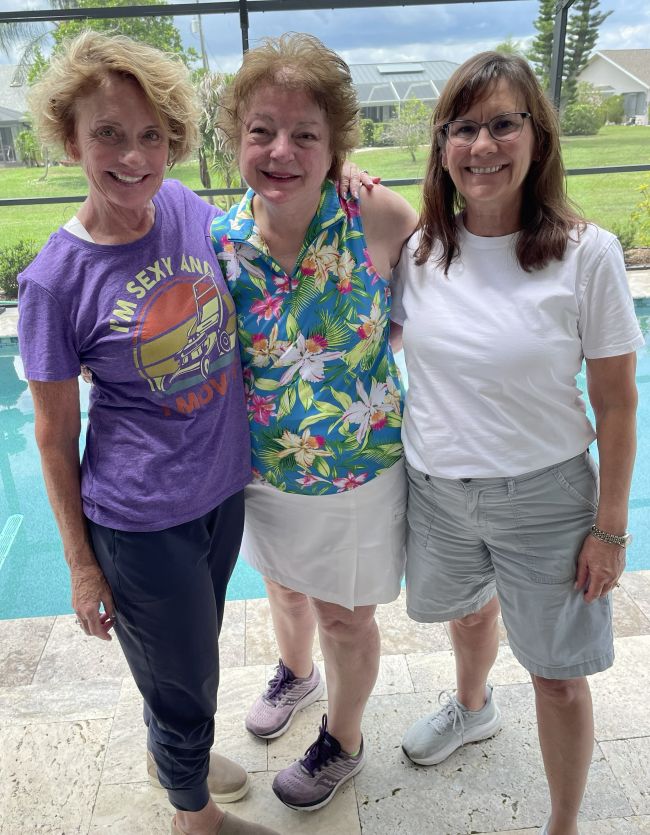 three friends standing next to a swimming pool